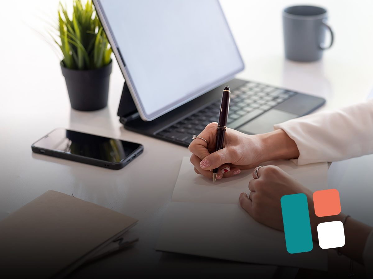 Werkplek met laptop, smartphone en iemand die notities maakt